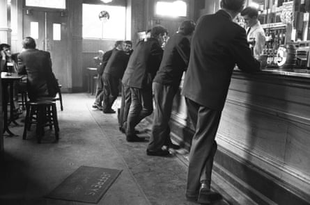 Men are lined up, leaning against a bar in a pub in the Gorbals district of Glasgow.