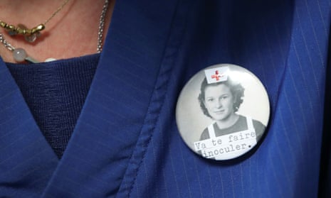 A Belgian healthcare worker wears a badge reading “Get inoculated.” 