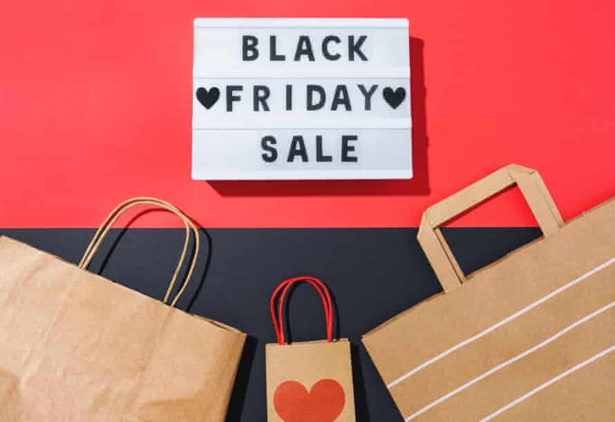 black friday in a light box and recycled paper bags on a black and red backgroundtop view with the words black friday sales on a light box and recyclable paper bags on equal parts red and black background. Signage dedicated to small and big business. online shopping