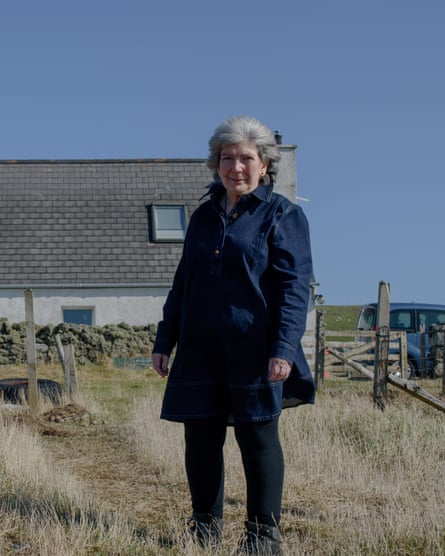 Kathy Coull, a traditional knitter and textile-maker, standing in a field outside her Fair Isle home.