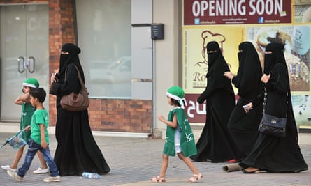 Saudi women and their children walk along a street in Riyadh