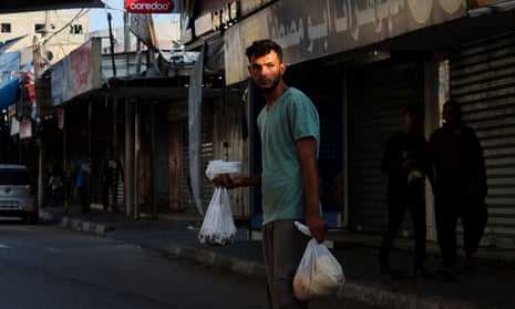 A Palestinian man crosses a street after getting food for his family in Khan Yunis, southern Gaza