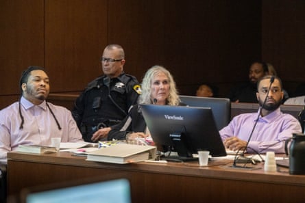 a woman and two men sitting at a table in courtroom