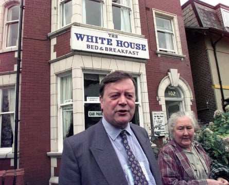 Kenneth Clarke and his wife outside a red-brick house that has now used as a B&B. A sign reading ‘The White House bed & breakfast’ can be seen on the outside of the building.
