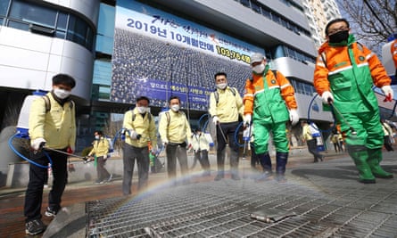 South Korean government officials spray disinfectant in front of the Daegu branch of the Shincheonji Church of Jesus