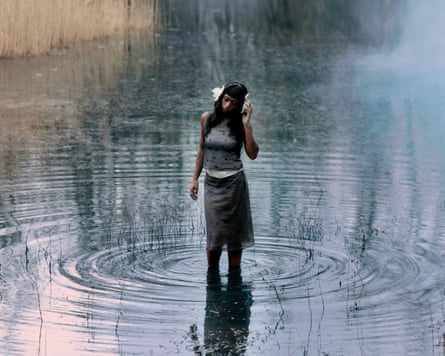 The musician Nia Archives standing in a rippling pond