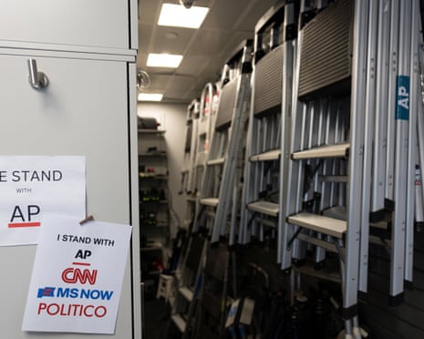 Signs supporting news outlets hang near stacked ladders in the White House media work area