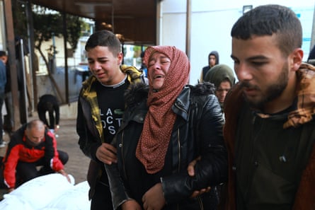 Relatives cry as bodies of Palestinians killed in Israeli bombings lie outside the morgue