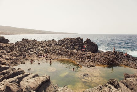 A pool surrounded by volcanic rocks on the shoreline