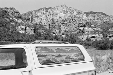 A truck’s rear window shows a drawn landscape, parked before real rocky cliffs in Arizona