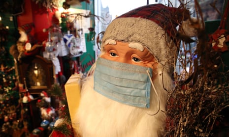 A santa with a face covering on at a Christmas shop