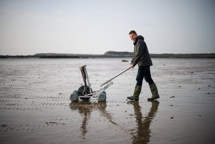 Rhun ap Iorwerth, the leader of Plaid Cymru, uses a specialised seeding machine to plant common eelgrass seeds in to the seabed at low tide.
