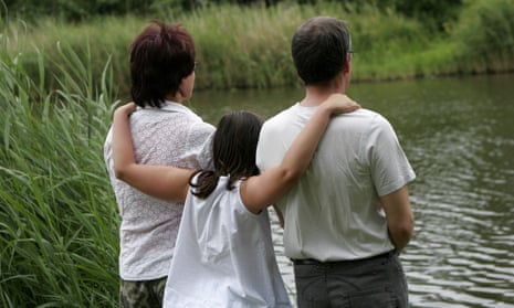 Two adults and child standing by river