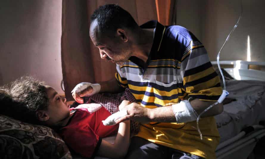Palestinian Ryad Eshkuntana, checks his daughter Suzy, as they receive medical care at al-Shifa hospital, 19 May. His wife and other children were killed in an Israeli air strike.
