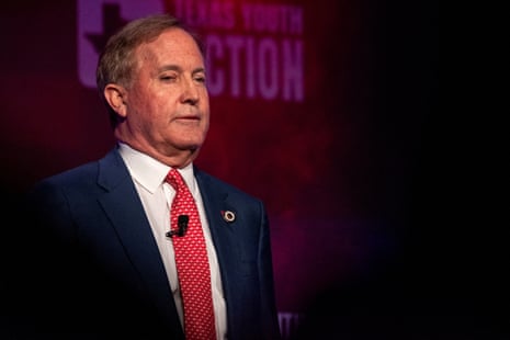 Ken Paxton, in a navy suit and red tie, speaks on stage at the Texas Youth Summit.