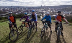 A group of mountain bikers pose for a photo in front of the Sheffield skyline.