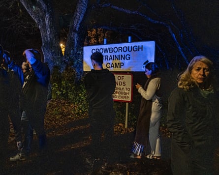 Protesters and police standing in the dark around a sign for Crowborough training camp