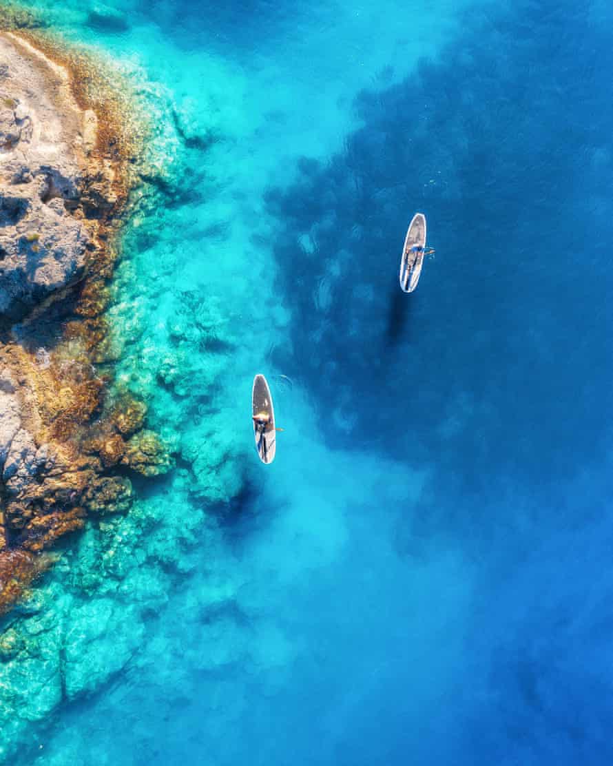 Aerial view of paddleboarders on blue sea.
