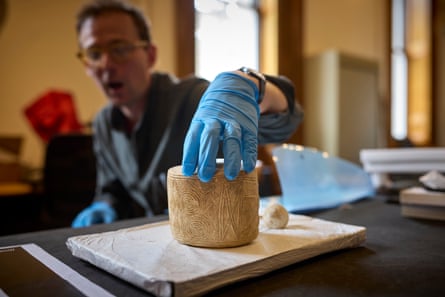 A curator wearing blue plastic gloves shows the Burton Agnes drum, a cylinder of decorated white chalk.