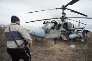 A man stands in front of a Russian Ka-52 helicopter gunship is seen in the field after a forced landing outside Kyiv