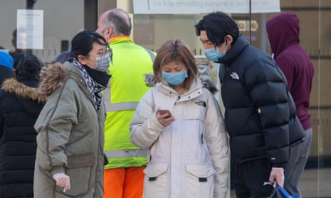 People wearing masks look at a mobile phone