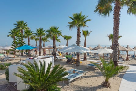 Beach scene with palms, loungers and sun umbrellas.