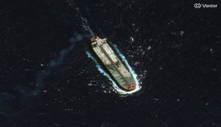 overhead satellite image of a broad, flat-decked oil tanker in a dark sea