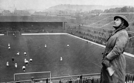 An air raid warden watches for enemy planes at a match between Charlton and Arsenal in London in 1940.