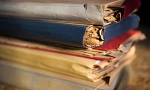A stack of several old folders stuffed with papers.