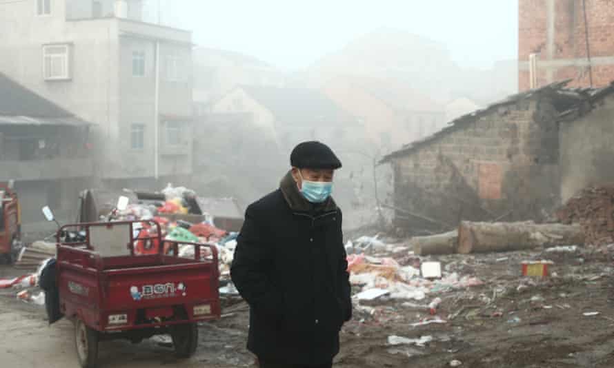 An old man wearing a medical mask walks in the village at sunrise in Jianli county, Hubei province.
