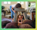 A woman builds a pillow fort with two children on a living room floor