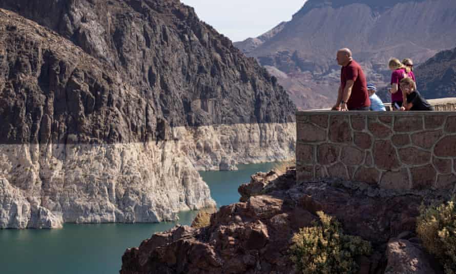 Tourists stand on a stone overlook at Lake Mead near Boulder City Nevada, looking out at the wide “bathtub ring” of lighter rock that indicates how much water levels have dropped.