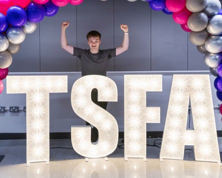 Hayden Bettson-Day puts his fists in the air behind a sign that says TSFA