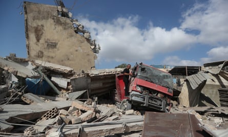 A vehicle buried in the rubble of destroyed buildings