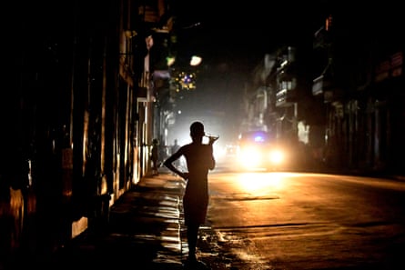 People stand in a dark Havana street at night