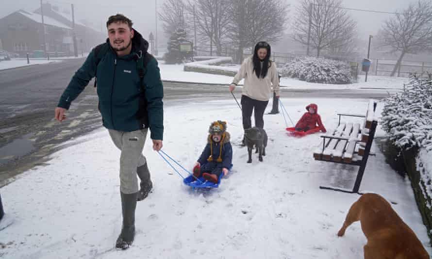 Adults pull children on sledges