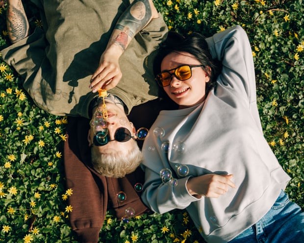 A young couple lying on grass blowing soap bubbles
