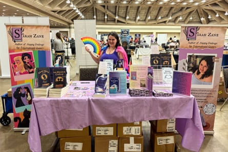 a woman smiles behind a table displaying books