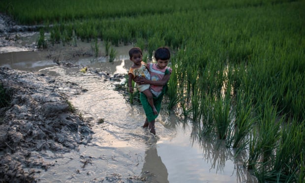 A young girl and a baby wade through mud after arriving in Bangladesh from Myanmar.