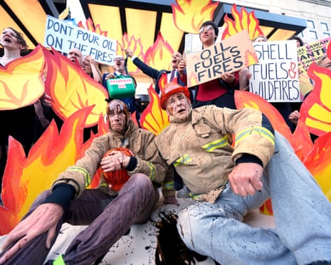 Fossil Free London campaigners dressed as a firefighters with a black liquid resembling oil poured over them, outside Shell UK Headquarters in London on Wednesday