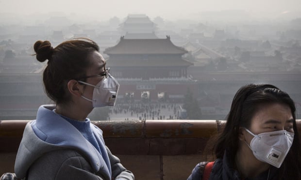 Chinese women wear masks as haze from smog caused by air pollution hangs over the Forbidden City in Beijing.