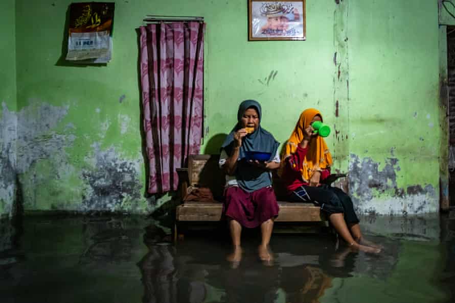 Parmini and her granddaughter Anisa have their Ramadan evening meal in their flooded home in Demak.