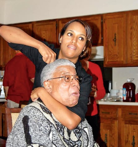 Kerry Washington standing up, with one arm around the neck of her father, Earl, who is seated in front of her