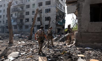 Two people in uniforms  near destroyed buildings
