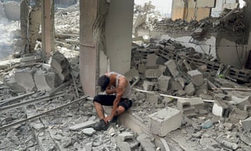 A Palestinian sits in the rubble of destroyed buildings following an operation by Israeli Special Forces in the Nuseirat camp.