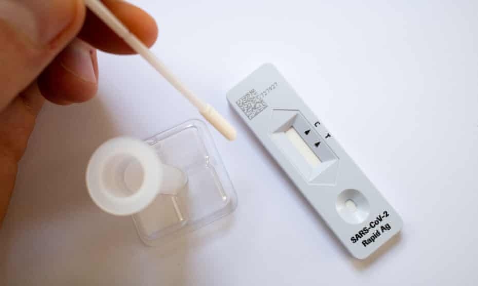 Image of a person using a Covid rapid antigen test. Their hand is holding a swab