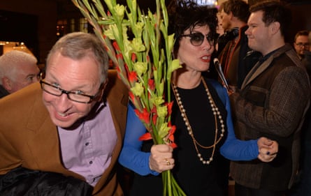 Ruby Wax holds a bunch of red gladioli while Ed Bye grins at the camera