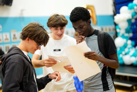 Three boys look at sheets of paper with their results; they look happy.