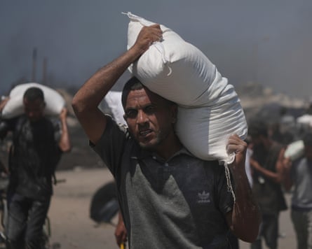People carry sacks of flour unloaded from a humanitarian aid convoy that reached Gaza City