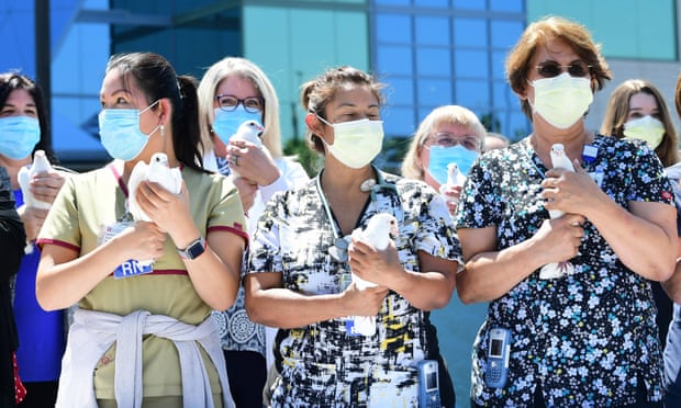 Nurses hold white doves before releasing them at a St Francis medical center event to thank the community for its support during the pandemic.
